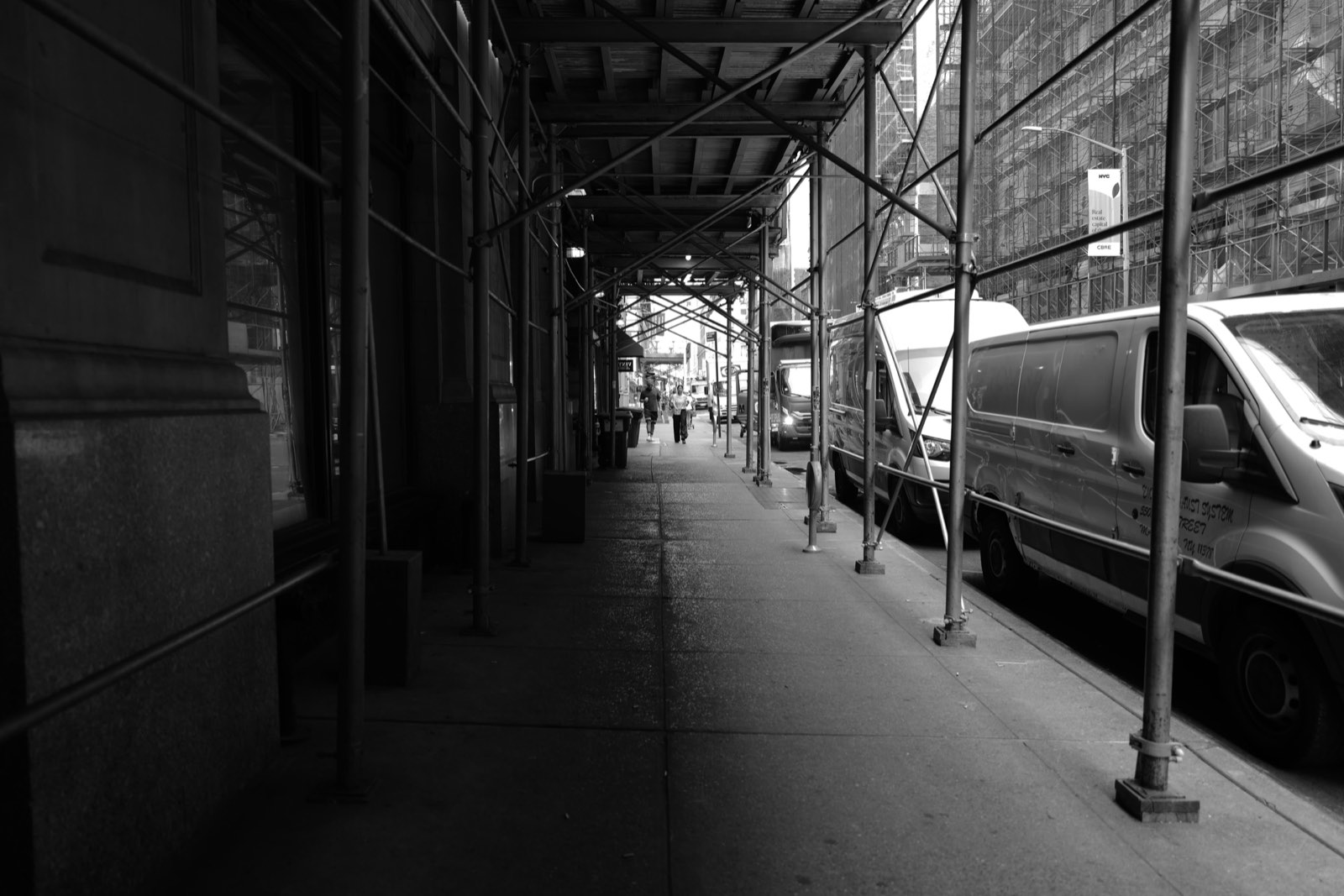 The covered sidewalk running under the construction scaffolding