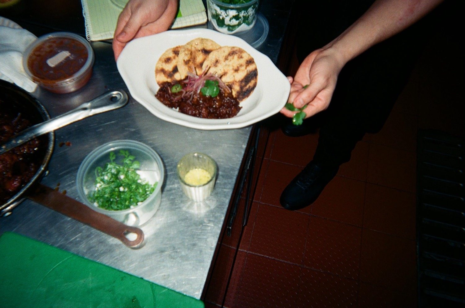 Vista cenital de un plato que se termina con cilantro junto a las tortillas asadas
