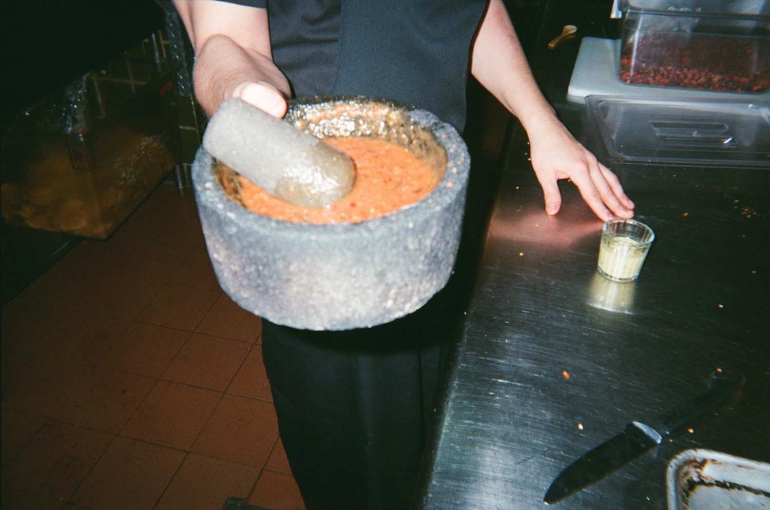 Un cocinero muele salsa roja en un molcajete de piedra sobre la barra de la cocina